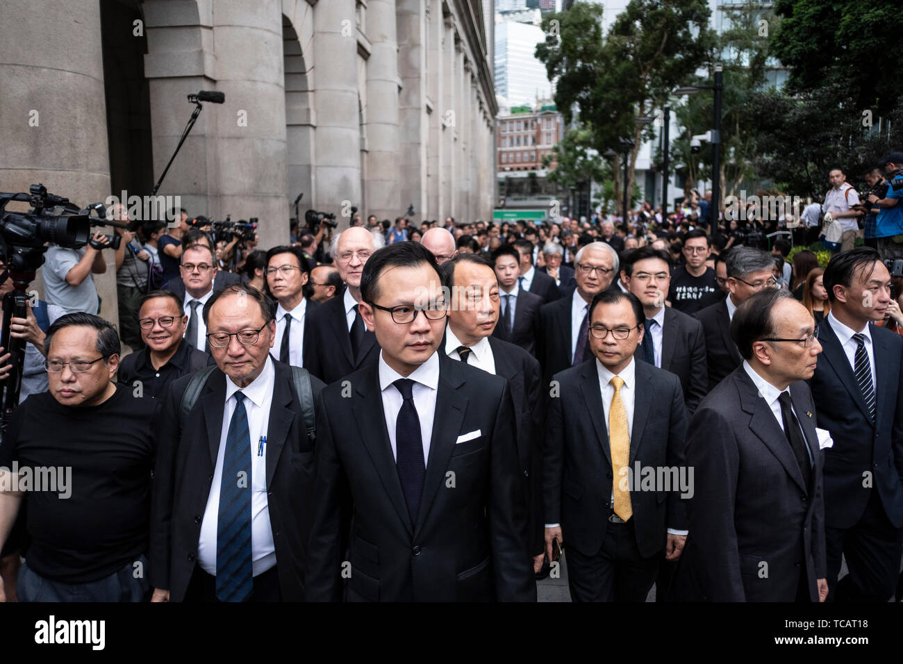 Legislatore e avvocato Dennis Kwok (centro) conduce la marcia silenziosa contro la legge in materia di estradizione. Centinaia di avvocati e professionisti legali abito nero di prendere parte durante la marcia silenziosa contro la legge in materia di estradizione da parte della Corte di appello al governo centrale complesso in Hong Kong. I critici la paura di qualsiasi accordo di estradizione potrebbe lasciare entrambe le figure aziendali e i dissidenti in Hong Kong vulnerabile alla Cina di tribunali politicizzato, fatalmente minando un business hub che ha prosperato spento la sua reputazione per un trasparente e un sistema giudiziario indipendente. Foto Stock