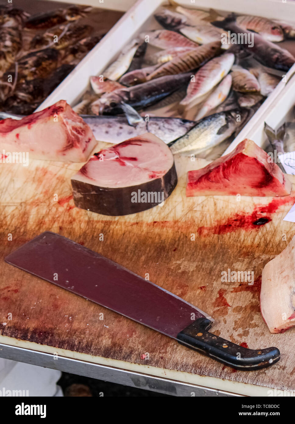 Chiudere la fotografia di fettine di pesce morto su un tavolo di legno con sangue e big cleaver. Animale il concetto di abuso, crudeltà nei confronti degli animali. Conservazione delle specie minacciate di estinzione. Problema globale. Foto: Catania, IT. Foto Stock