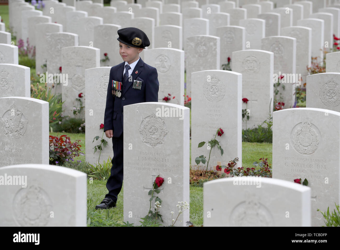 Sei-anno-vecchio George Sayer, da Chipping Ongar in Essex, indossando le medaglie del suo prozio anche chiamato George Sayer, viste le lapidi seguendo il Royal British Legion di servizio del ricordo, presso la Commissione delle tombe di guerra del Commonwealth il cimitero di Bayeux, Francia, come parte delle celebrazioni per il settantacinquesimo anniversario dello sbarco in Normandia. Foto Stock