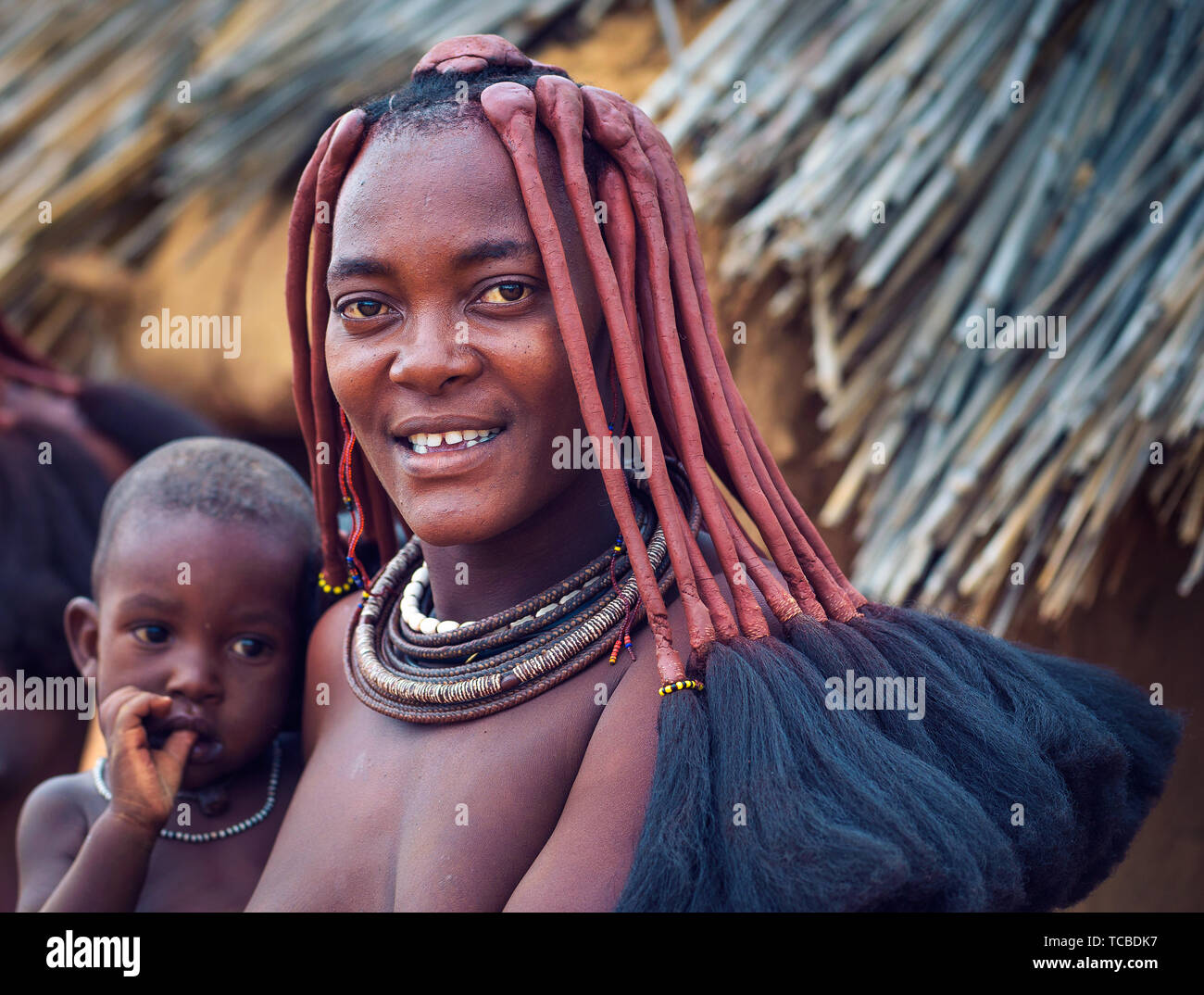 Ritratto di una giovane donna himba con suo figlio indossando il tradizionale acconciatura Foto Stock