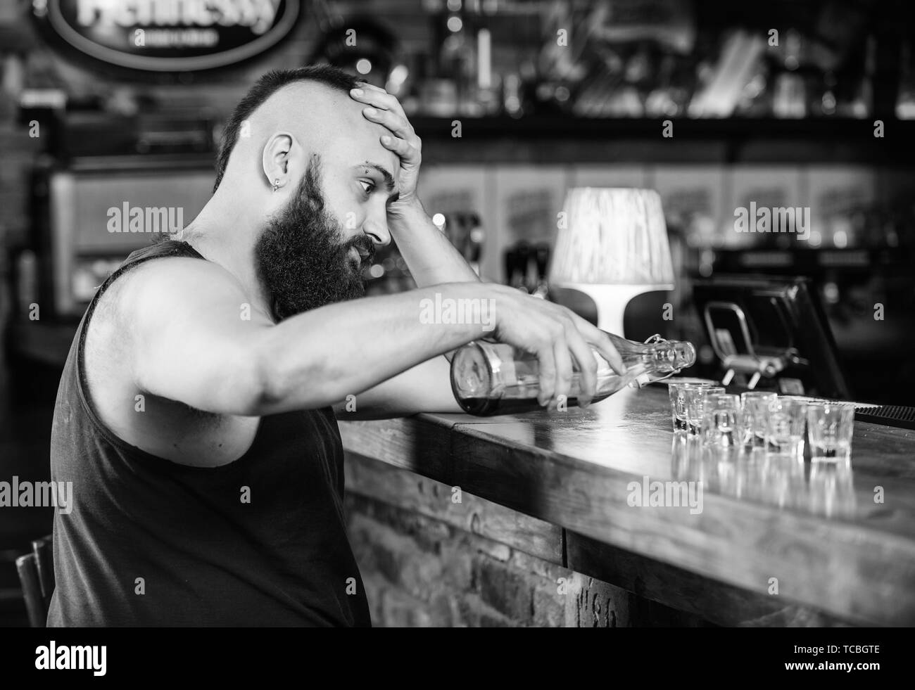 L'alcol addicted concetto. Tanga uomo brutale di bere alcol ordinare più bevande al banco bar. Guy trascorrere il tempo libero nel bar con alcolici. L'uomo ubriaco sedersi da solo nel pub. L' alcolismo e depressione. Foto Stock