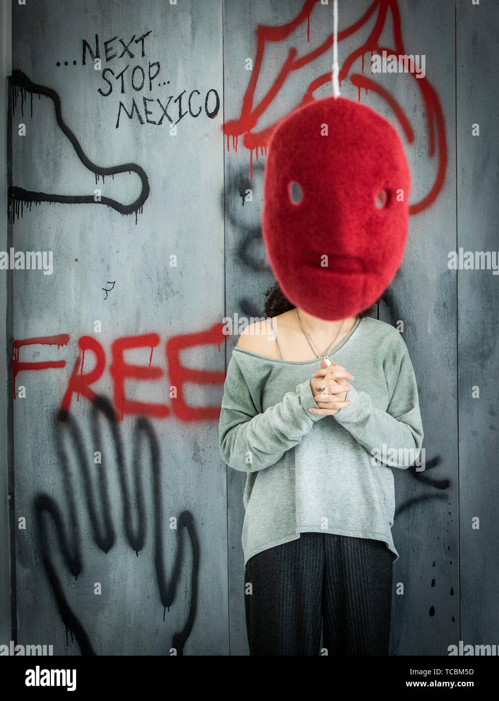 Una maschera da un lavoro intitolato La paura e l'amico artista Lucia Bowley oscura il volto di Mariam Shaath come lei si trova di fronte il suo lavoro intitolato solo la terra SA, entrambe le opere d'arte formano parte della raffinata arte mostra di laurea presso l'Università di Leeds. Foto Stock