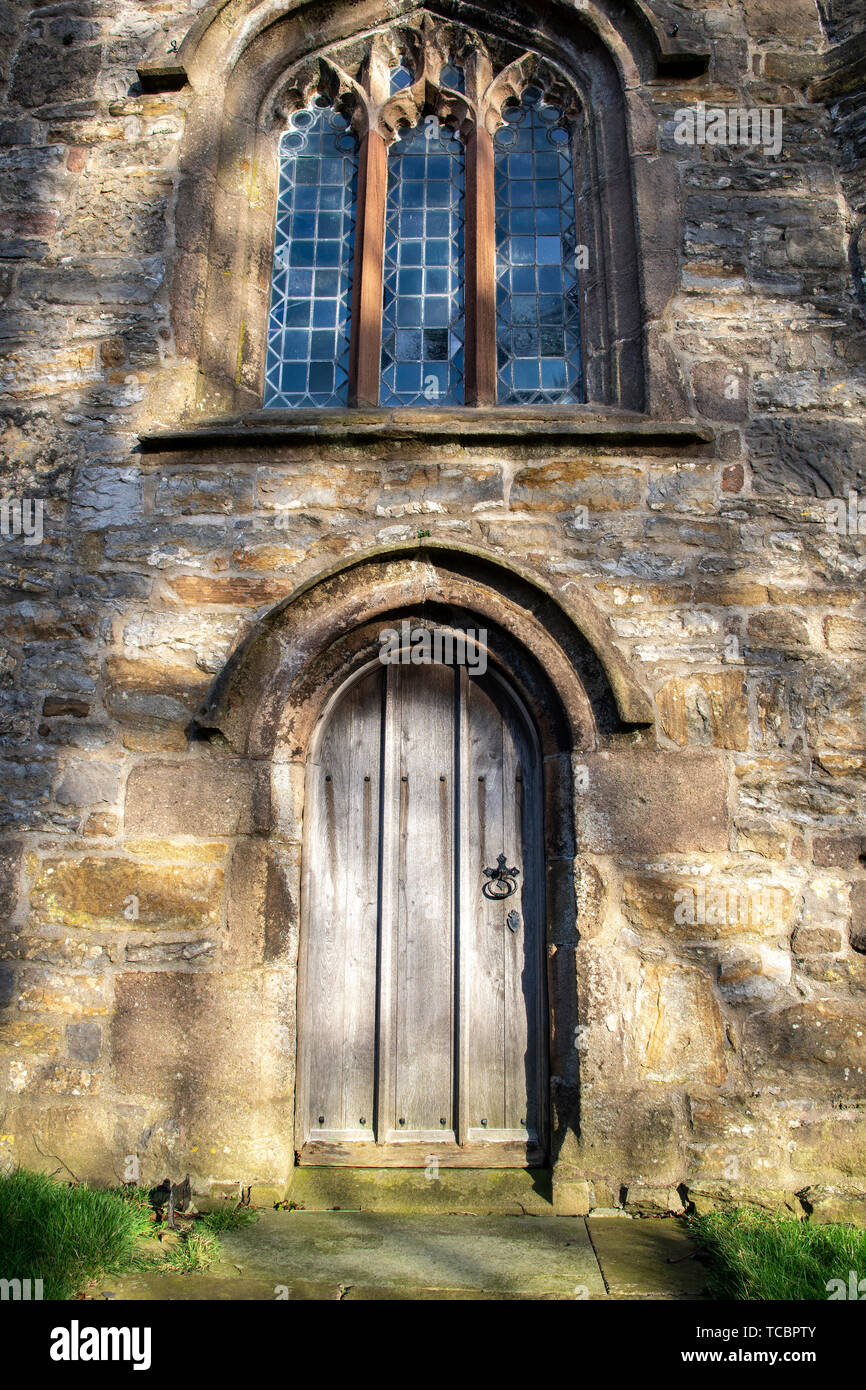 Il pittoresco villaggio di Downham, Lancashire, in serata sole,Ribble Valley, Regno Unito stile gotico porta di legno con la pietra ingresso ad arco di Foto Stock