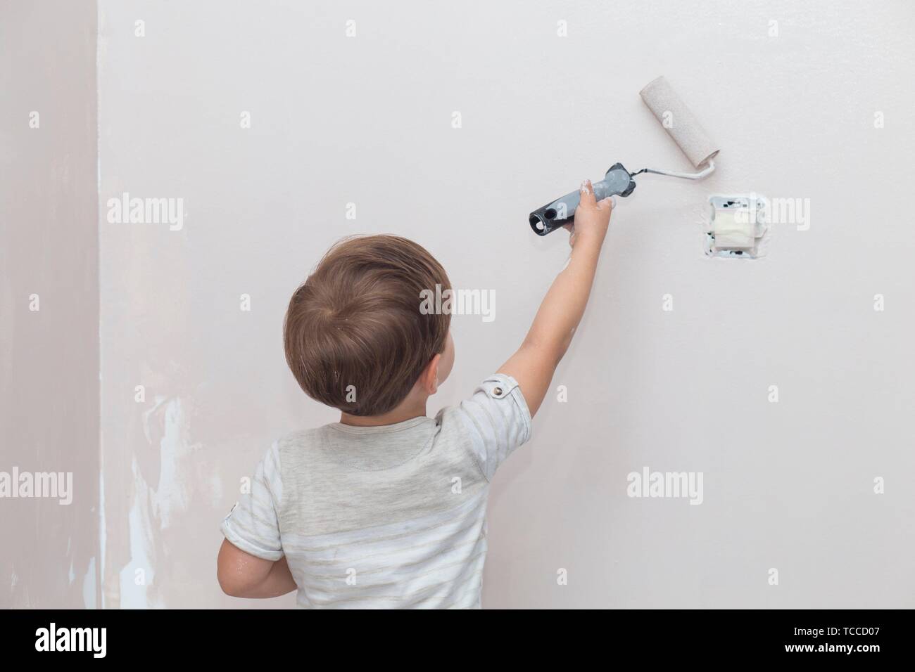 3 anni carino piccolo ragazzo con rullo di vernice in mano. Bambini aiutando Casa concetto. Foto Stock