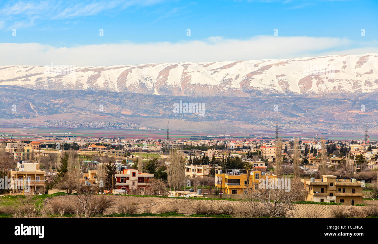 Case libanese in Valle Beqaa con cappuccio di neve montagne sullo sfondo, Baalbeck, Libano Foto Stock