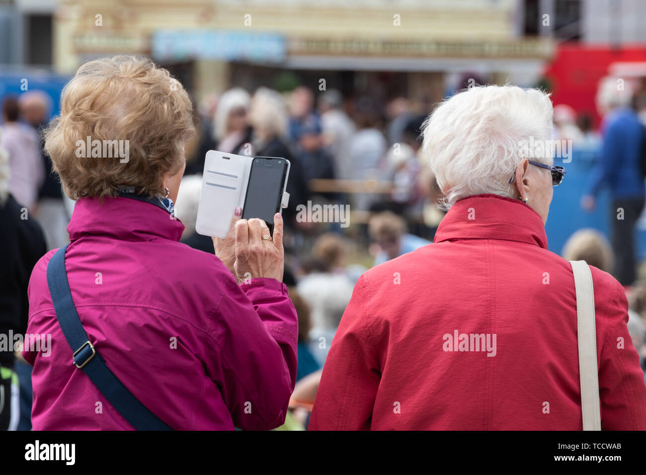Le donne anziane in piedi mentre si scatta una foto con il suo telefono cellulare o telefono cellulare Foto Stock