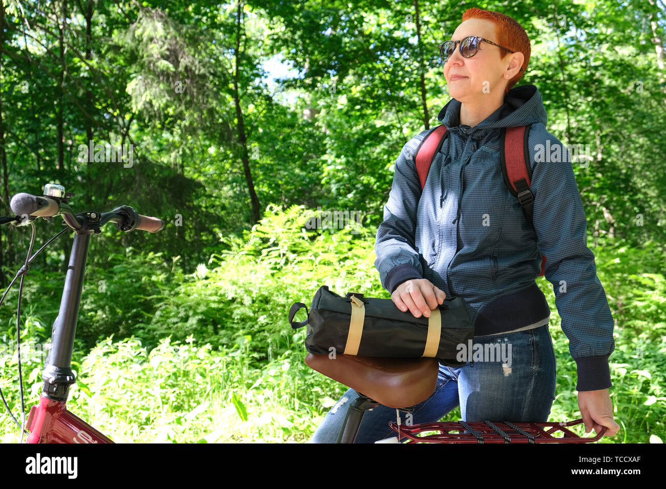 La ragazza sorride felicemente. Passeggiate a cavallo nel parco su una pista ciclabile. Faccia esposta alla luce solare Foto Stock