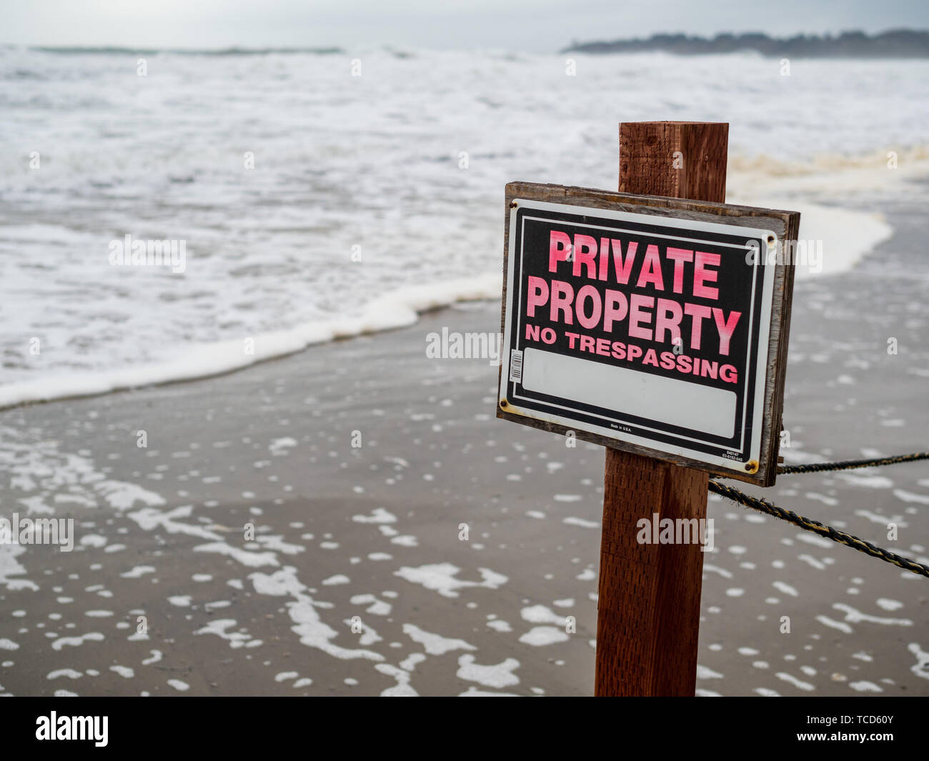 La proprietà privata senza sconfinamenti di firmare la pole e recinto di filo su proprietà sulla spiaggia accanto alle onde Foto Stock
