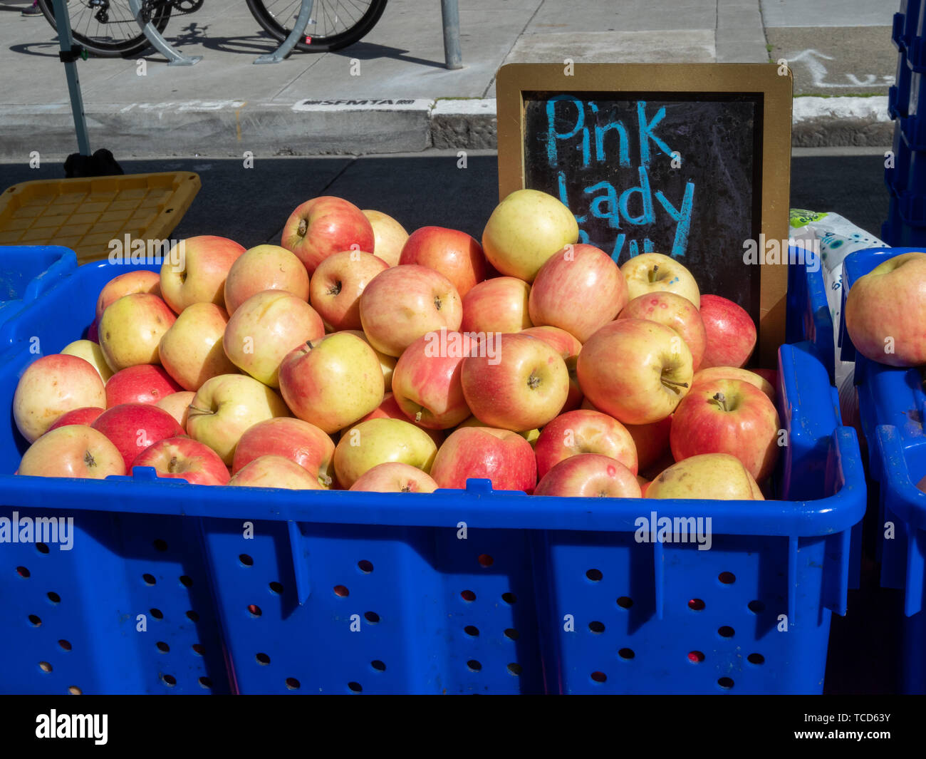 Pila di Pink Lady mele in blu carrello sulla giornata di sole al mercato all'aperto Foto Stock