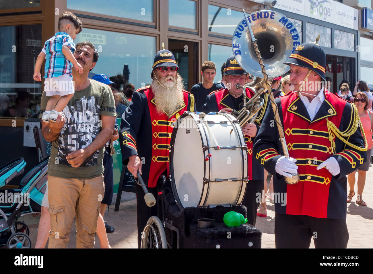 Funny belga uomo tre marching band / fanfare band / brass band De Rustende Moeders giocando il sousaphone e bass drum sulla strada in Belgio Foto Stock