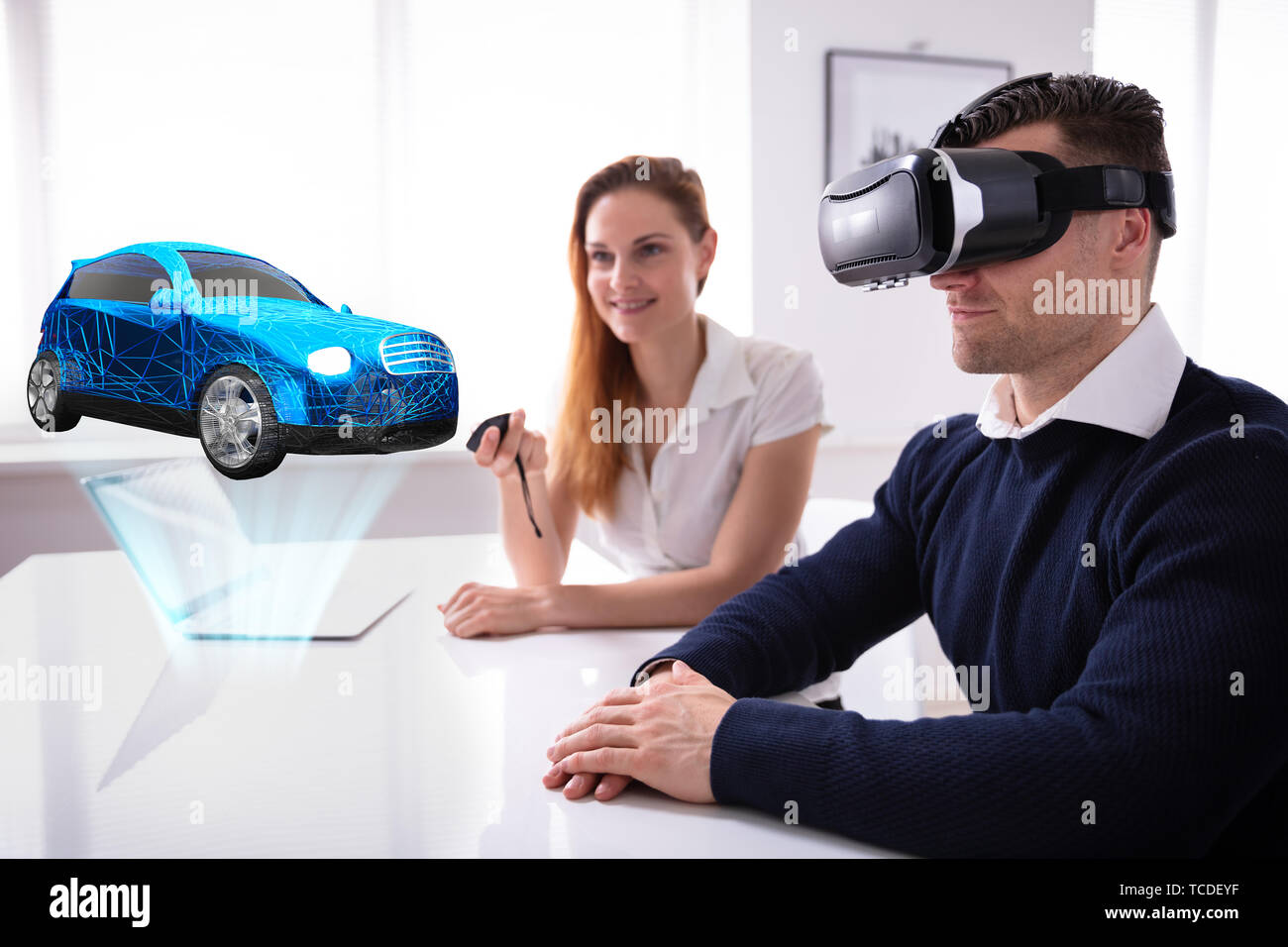 Uomo che indossa le cuffie VR guardando al modello di auto con agente femmina Holding Remote Foto Stock