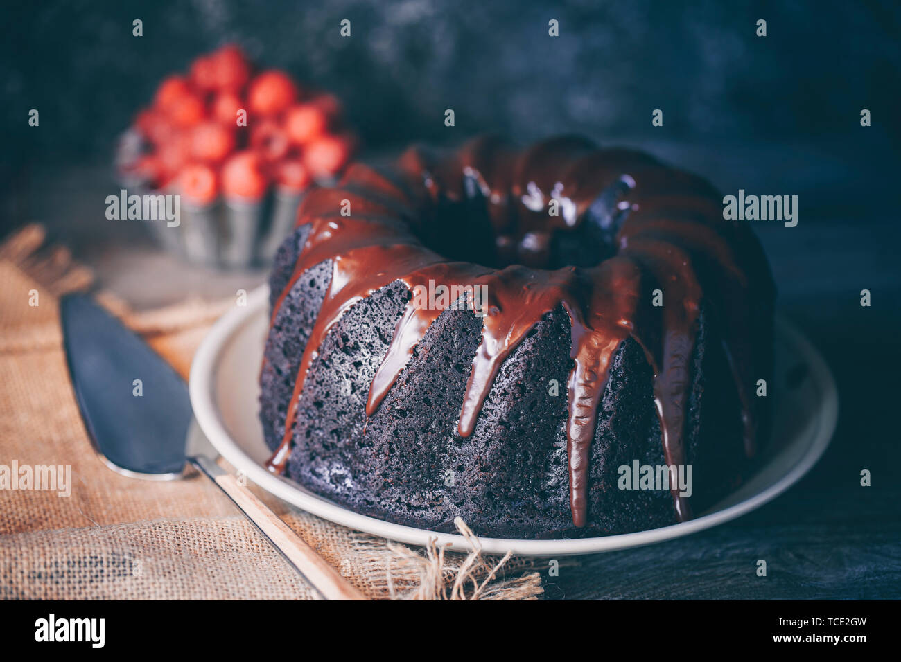 Devil's food torta ricoperta di cioccolato fuso e una ciotola di lamponi freschi Foto Stock