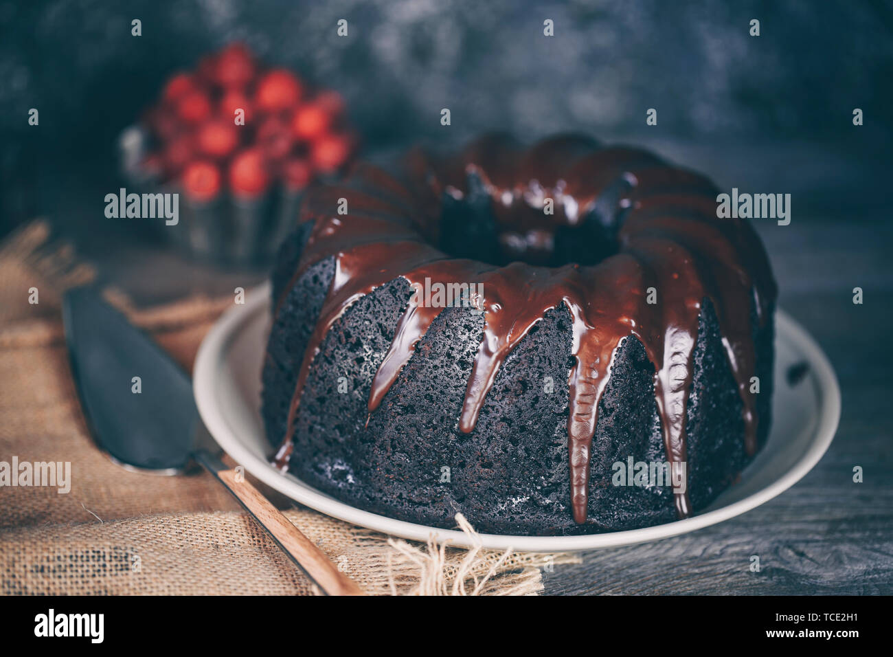 Devil's food torta ricoperta di cioccolato fuso e una ciotola di lamponi freschi Foto Stock