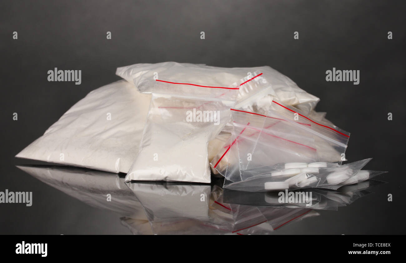 La cocaina e le droghe in pacchetti su uno sfondo grigio Foto Stock