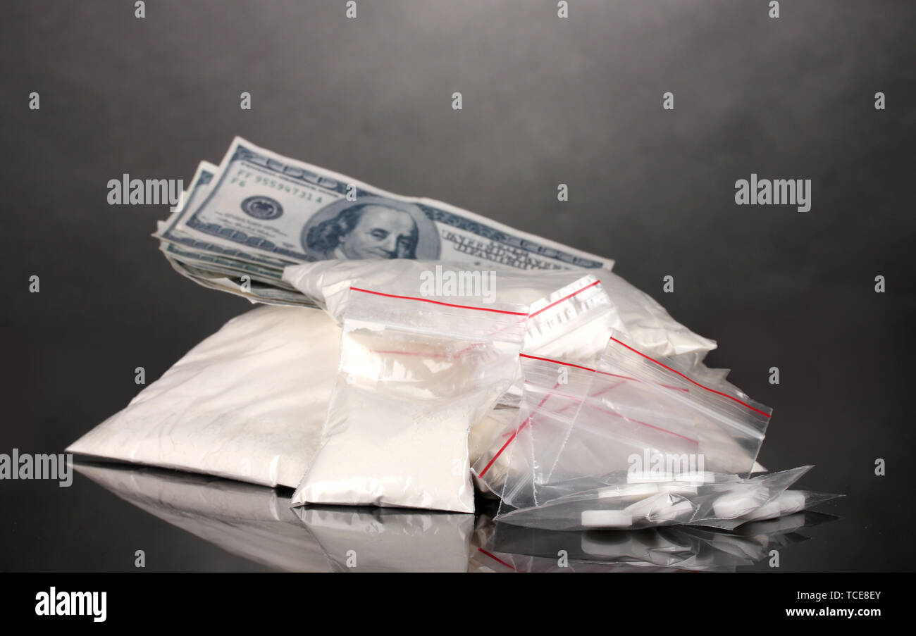 La cocaina e le droghe in pacchetti di dollari su sfondo grigio Foto Stock