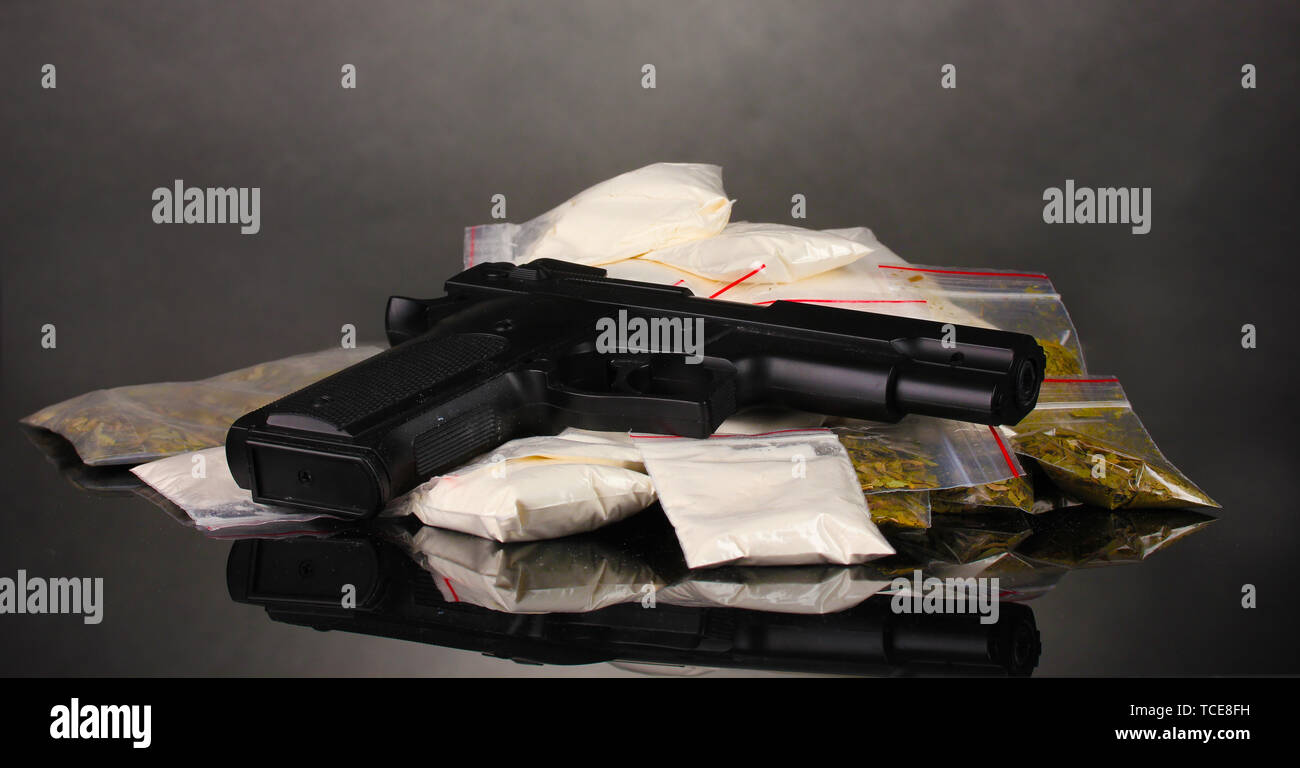 Cocaina e marijuana in pacchetti e pistola su sfondo grigio Foto Stock