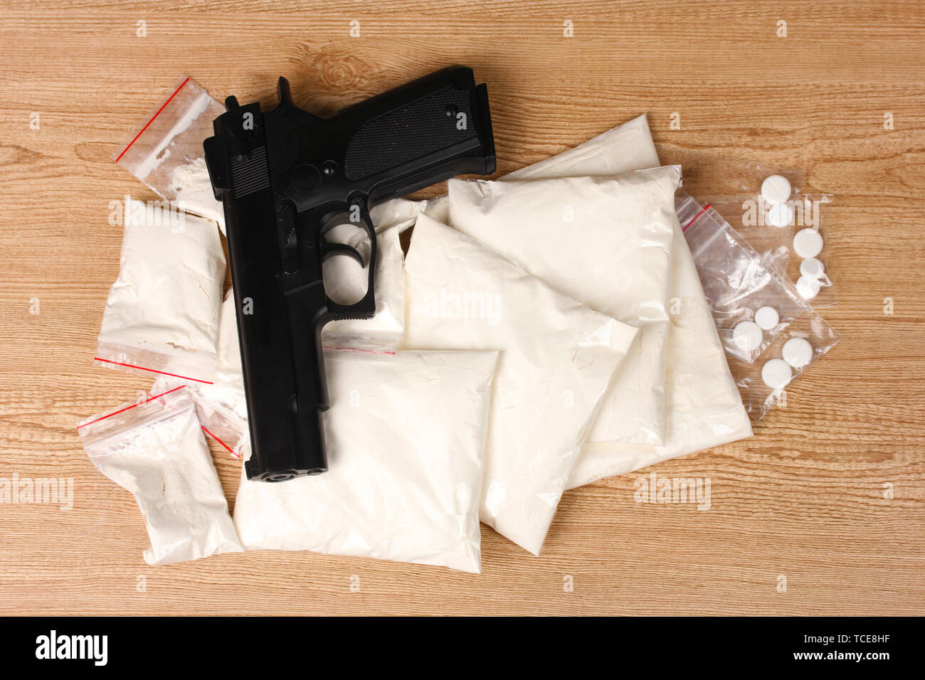 Cocaina e marijuana in pacchetti e pistola su sfondo di legno Foto Stock