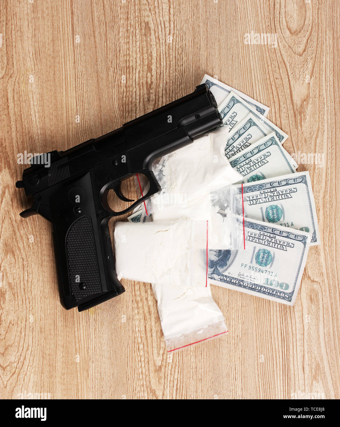 La cocaina nei pacchetti di dollari e pistola su sfondo di legno Foto Stock