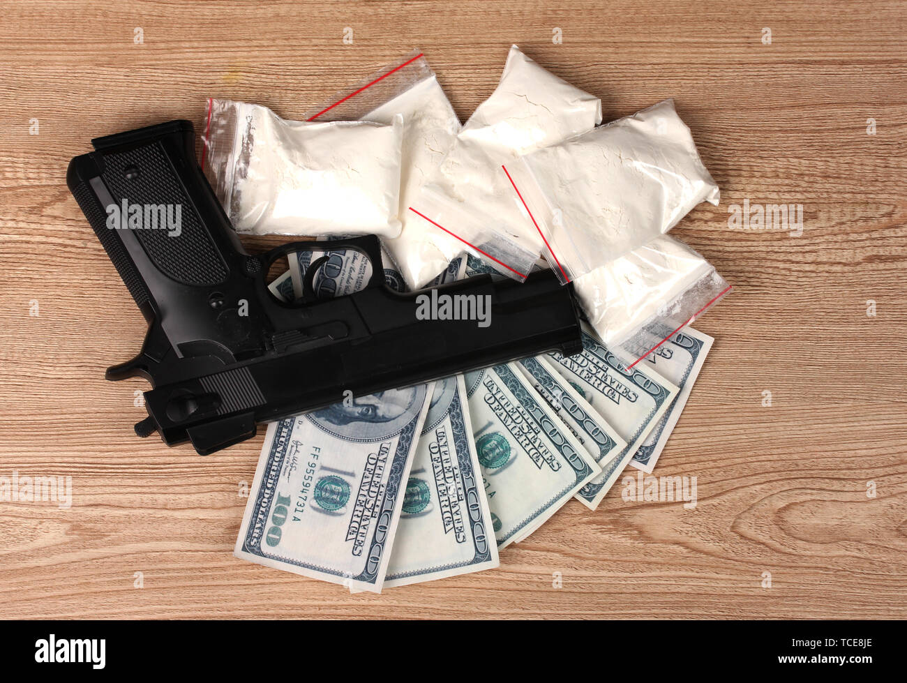 La cocaina nei pacchetti di dollari e pistola su sfondo di legno Foto Stock