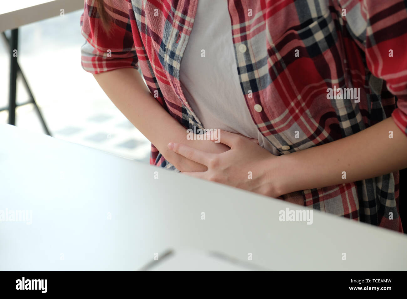 Ragazza donna toccando lo stomaco con dolore male della sofferenza da stomachache periodo mestruale crampi al lavoro Foto Stock