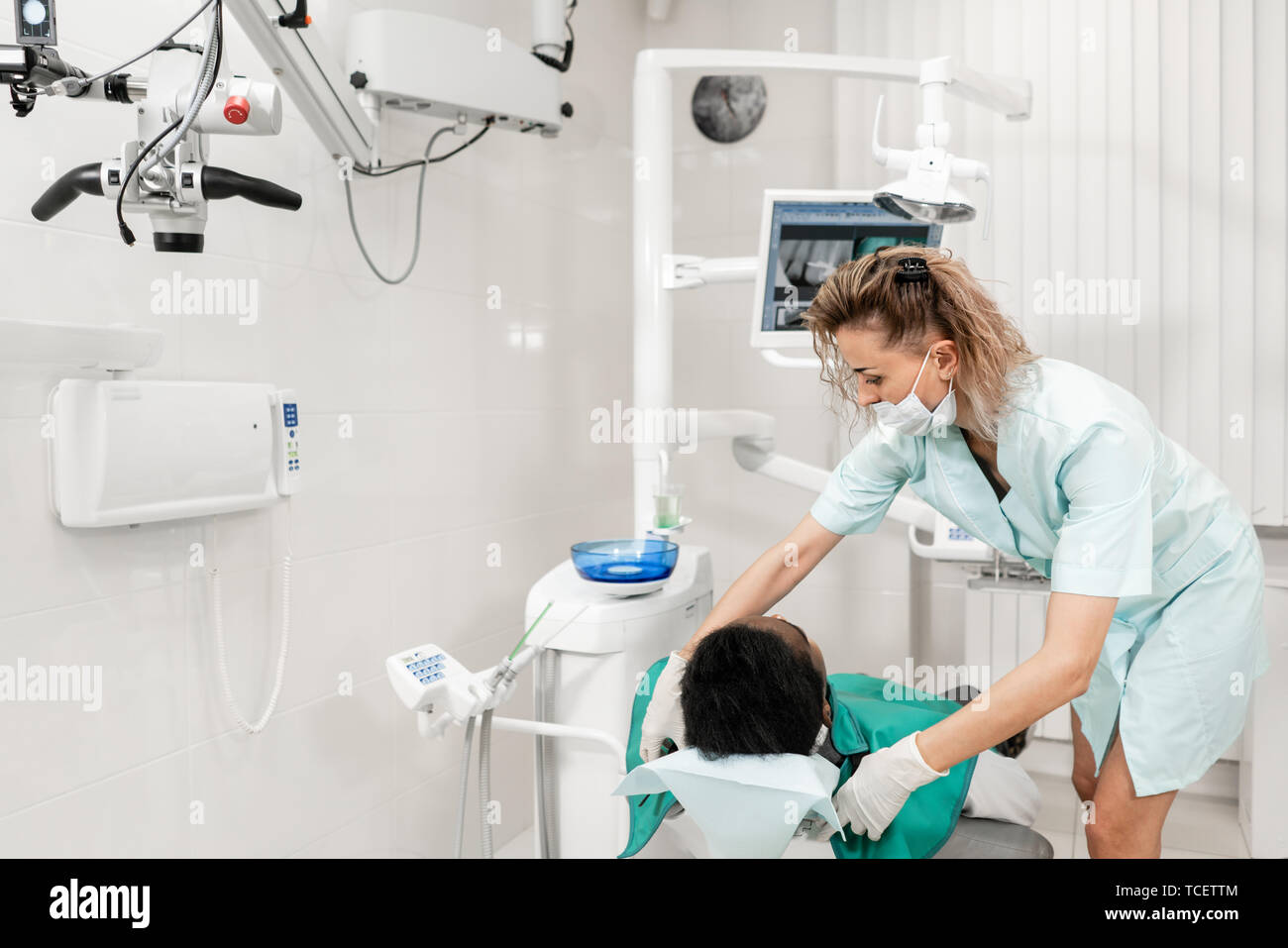 Donna dentista utilizzando raggi x macchina, paziente sdraiato su una sedia in odontoiatria. Giovane americano africano maschio con cattivo denti. Medicina, salute stomatologia Foto Stock