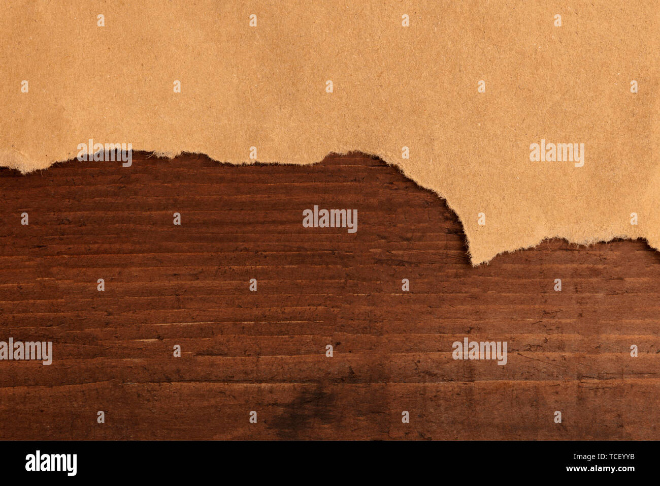 Un pezzo di strappata marrone carta craft, girato da sopra al buio su un rustico sfondo di legno, un design grunge con copyspace Foto Stock