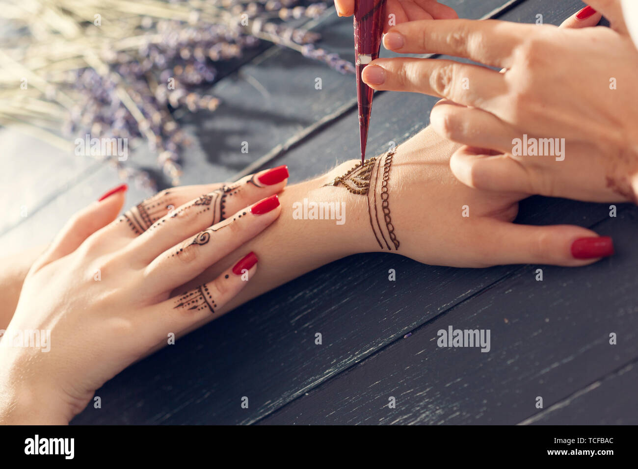 Il processo di applicazione della mehndi sulle mani femminili Foto Stock