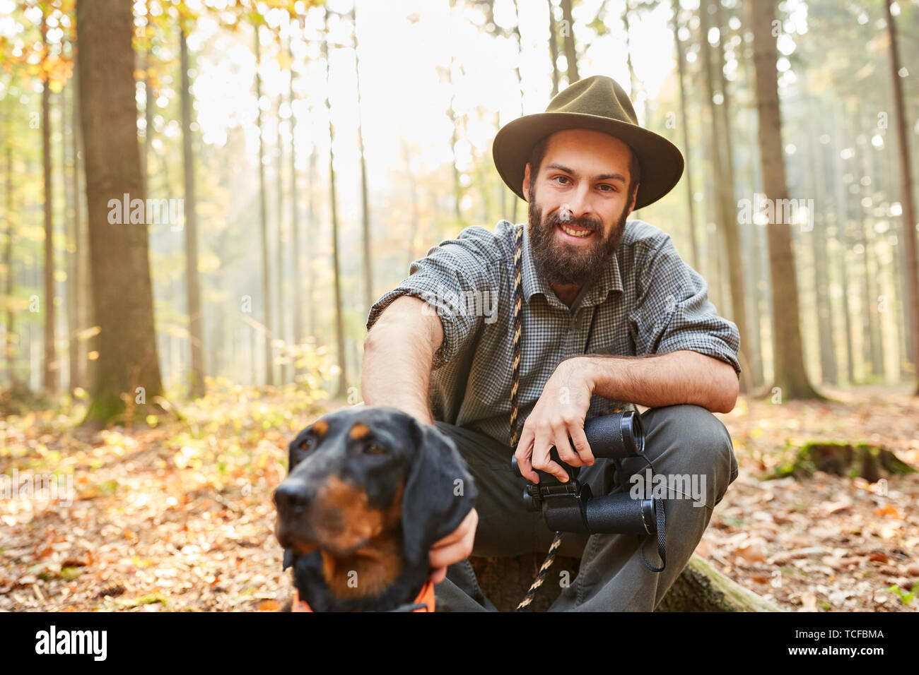 Forester con cane da caccia e binocoli prende una pausa nella sua foresta Foto Stock