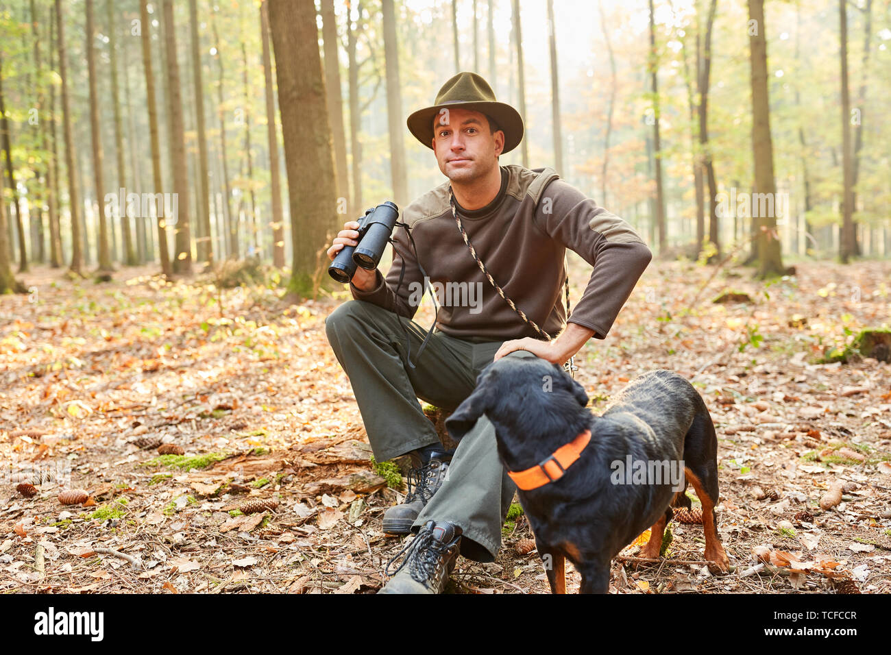 Forester o cacciatore con un cane come un cane da caccia e binocoli nell'area forestale Foto Stock