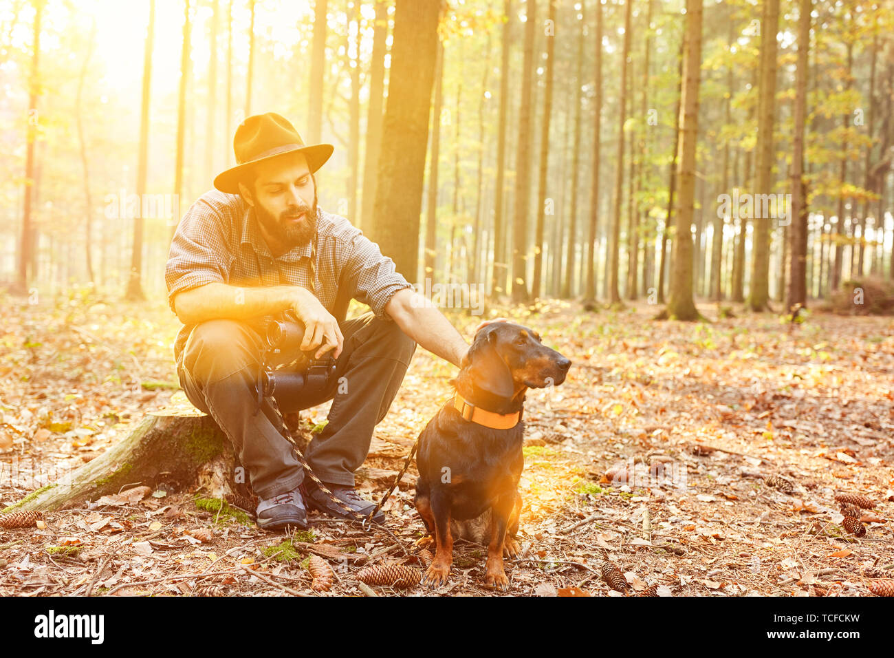 Ranger con il suo cane nei Boschi è seduta su un moncone durante una pausa Foto Stock