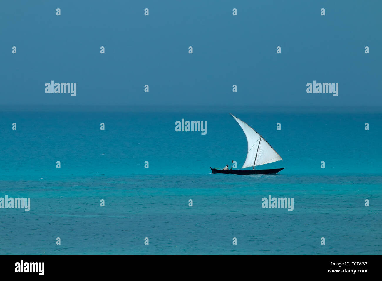 Imbarcazione a vela in legno (dhow) sull'acqua con cielo nuvoloso, isola di Zanzibar Foto Stock
