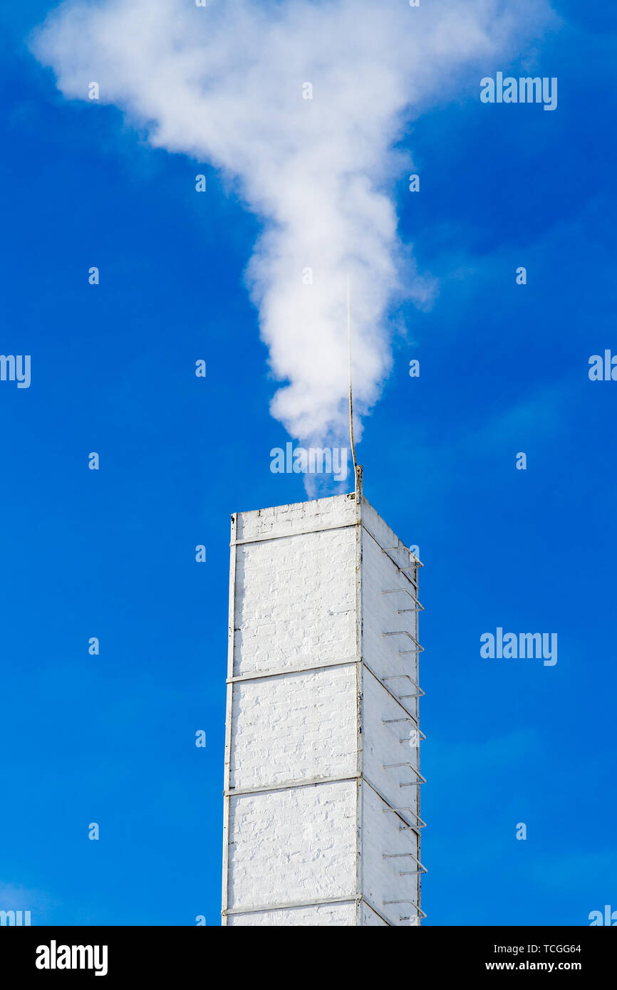 Fumante tubo bianco contro il cielo blu. Foto Stock