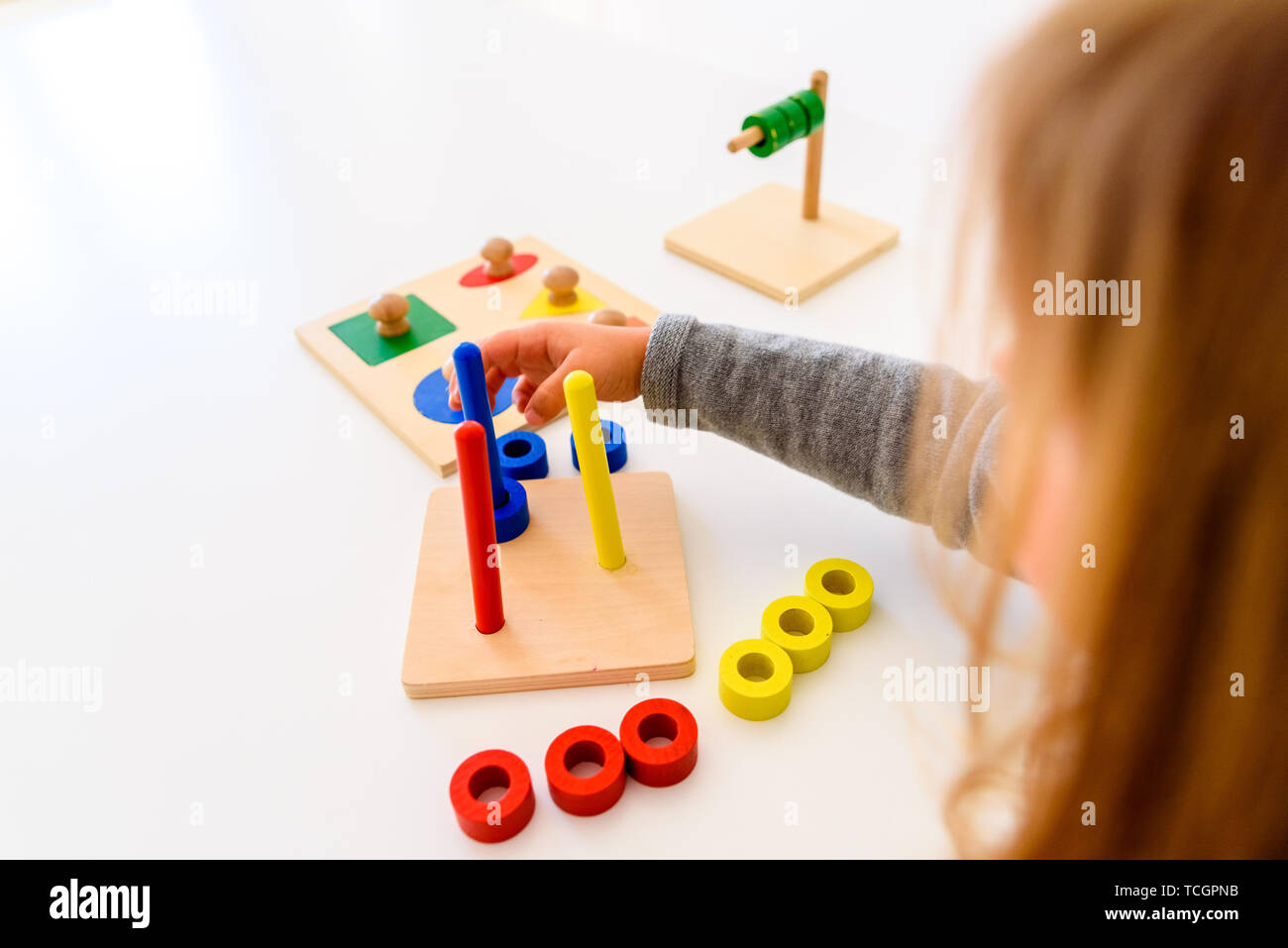 Ragazza a sviluppare la sua abilità manuale con un materiale sensoriale di colori. Foto Stock