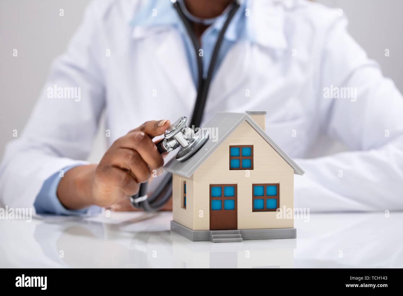 Close-up di un medico di controllo a mano il modello semplice casa con uno stetoscopio Foto Stock