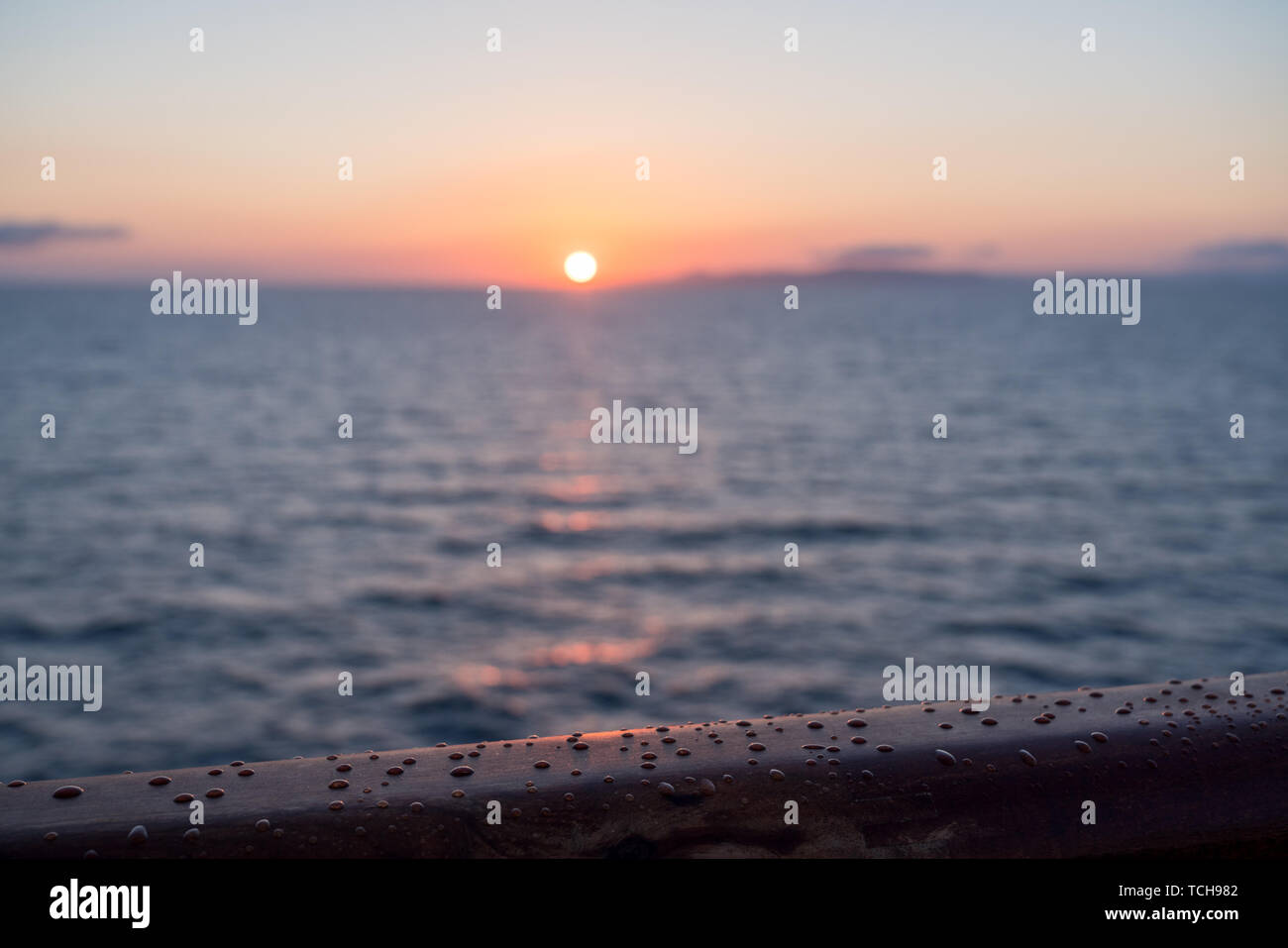 Gocce di pioggia sulla ringhiera in teak di nave da crociera al tramonto o alba Foto Stock