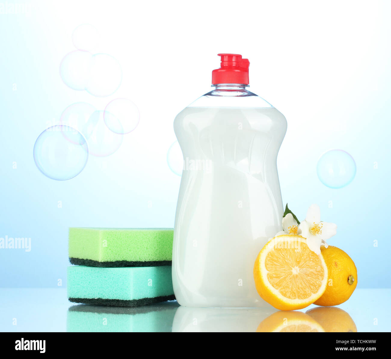 Detersivo liquido per stoviglie con spugne e limone con fiori su sfondo blu Foto Stock