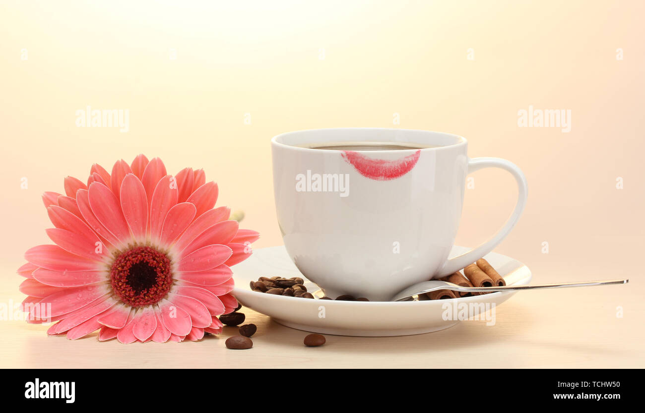 Tazza di caffè con marchio di rossetto e gerbera fagioli, bastoncini di cannella sul tavolo di legno Foto Stock