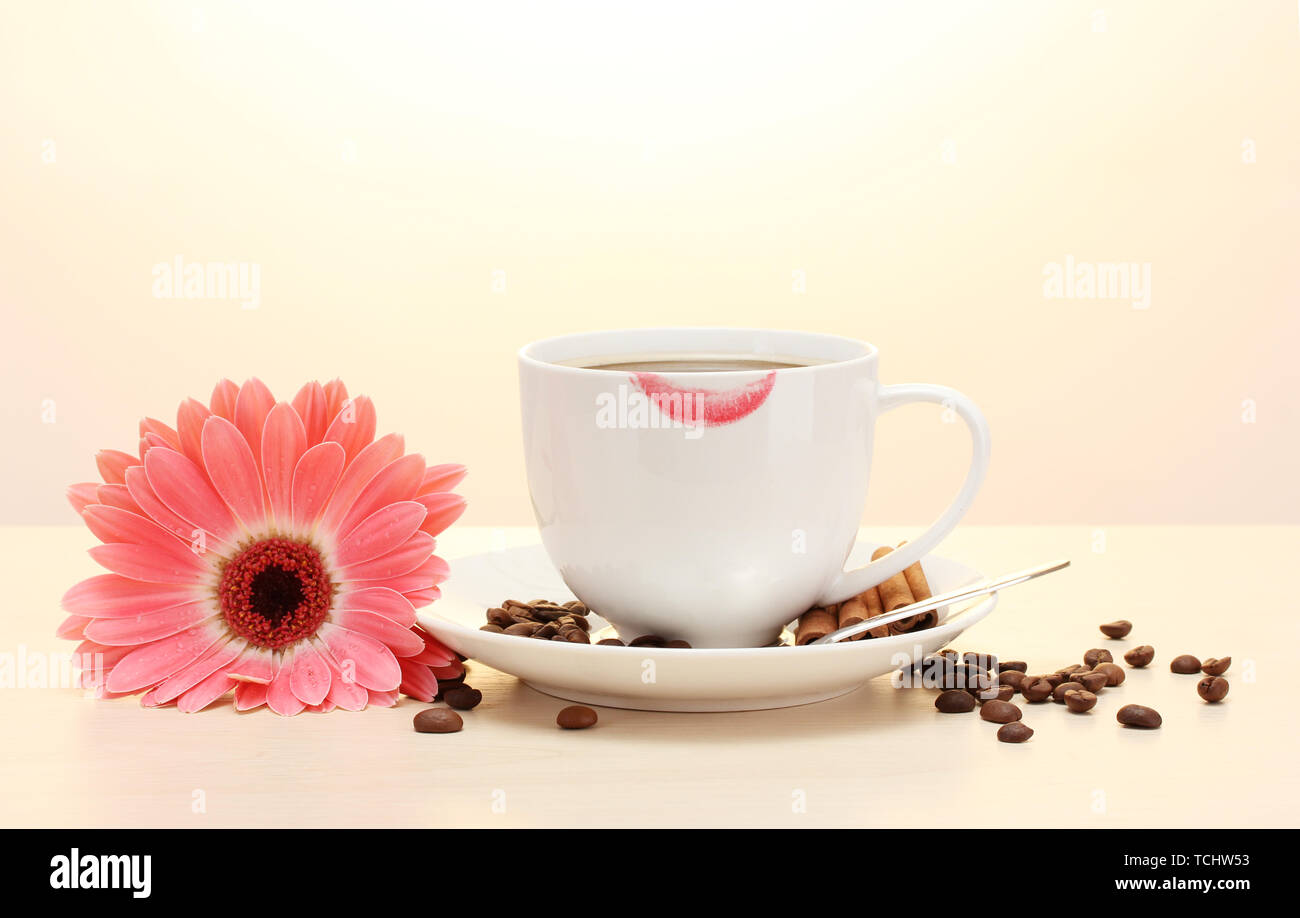 Tazza di caffè con marchio di rossetto e gerbera fagioli, bastoncini di cannella sul tavolo di legno Foto Stock