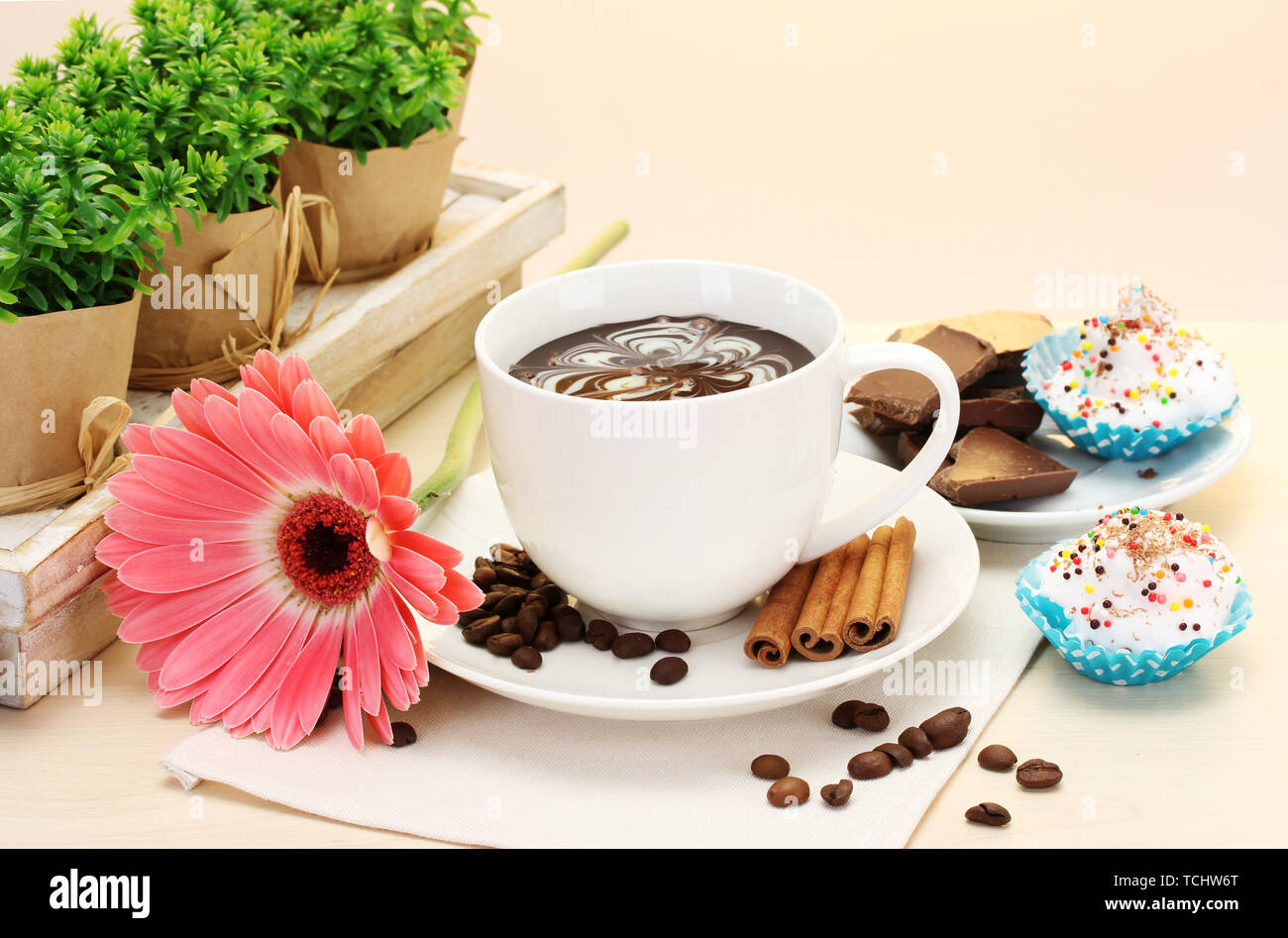 Tazza di caffè e gerbera fagioli, bastoncini di cannella sul tavolo di legno Foto Stock