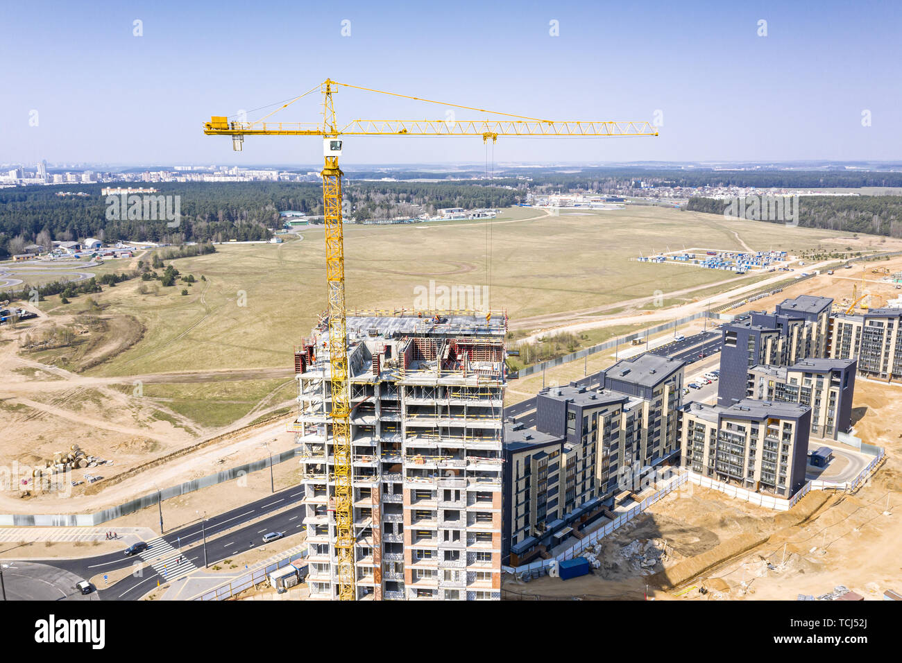 Drone immagine della città sito in costruzione con giallo Industrial Gru a torre alto permanente sul cielo blu sullo sfondo Foto Stock