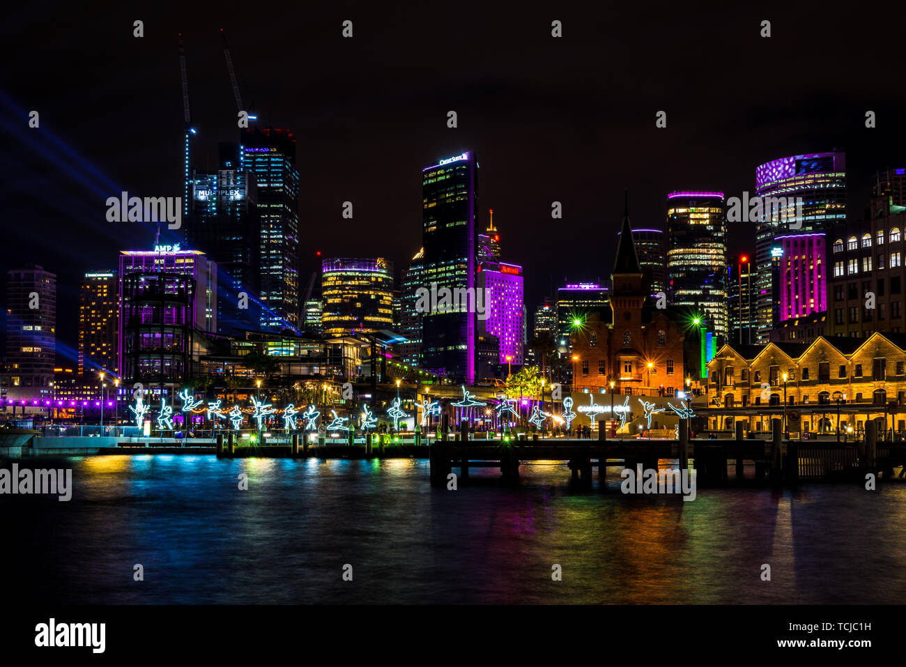 I ballerini di salto in tutta l'acqua in Sydney, con lo skyline della città in lontananza durante il vivace, il popolare annuale festival della luce. Sydney, Australia Foto Stock