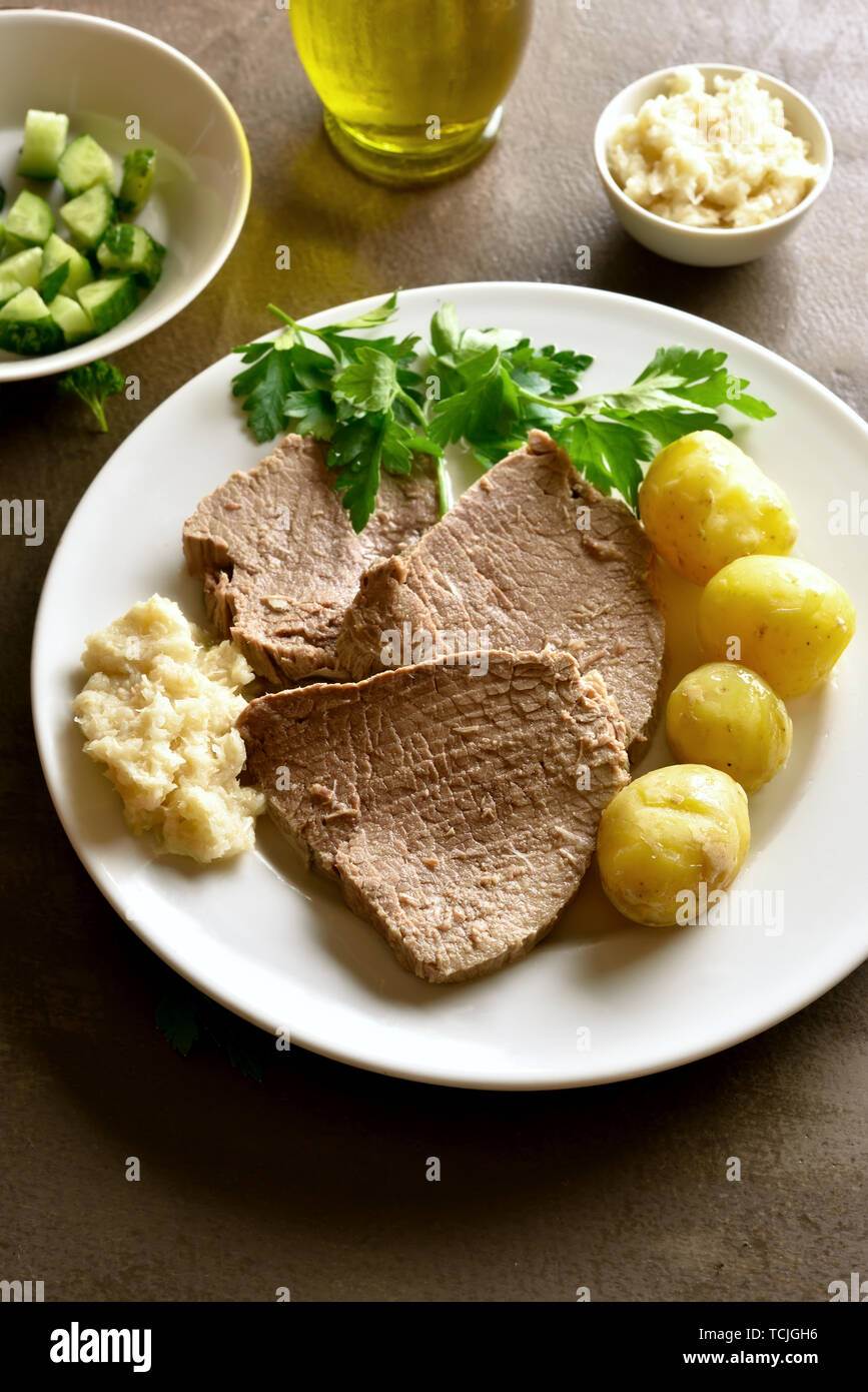 Tafelspitz, bollito di manzo con patate e rafano su sfondo marrone. Foto Stock