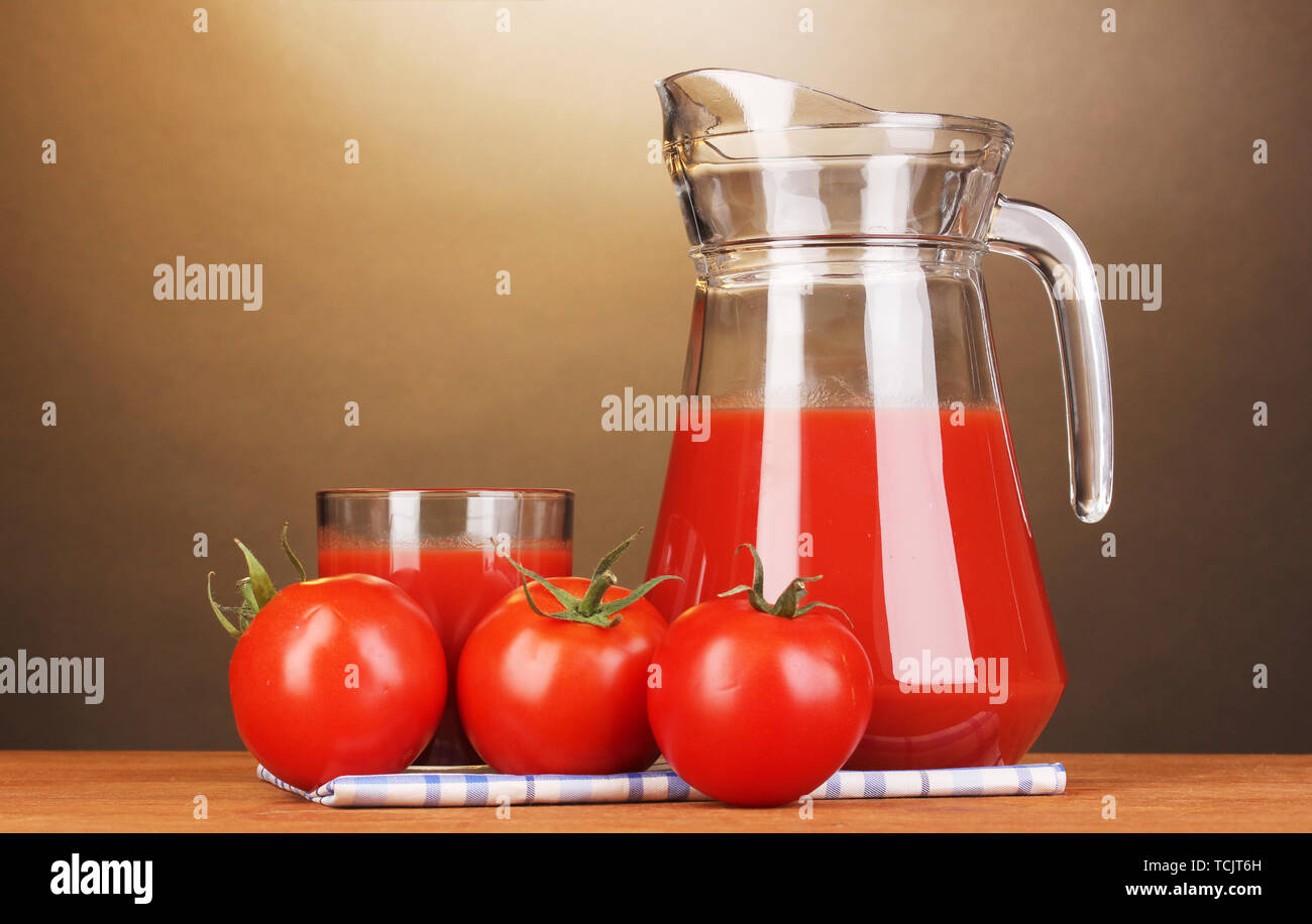I succhi di pomodoro nella brocca e vetro su un tavolo di legno su sfondo marrone Foto Stock