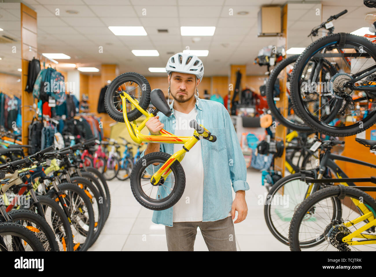 L uomo nel casco vale per bambini, bicicletta negozio di sport Foto Stock