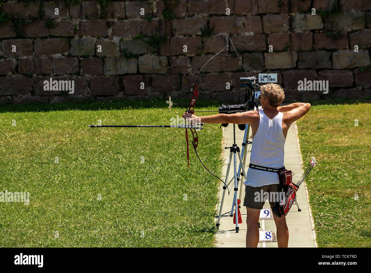 Barcellona, Spagna - Giugno 11th, 2014: un uomo adulto è la formazione in tiro con l'arco con un olympic ottiene bow accanto al castello di Montjuic, Barcellona hill Foto Stock