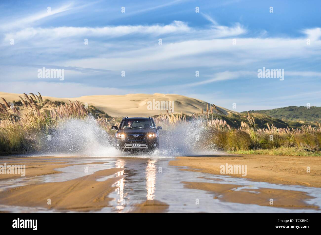 Nero Hyundai Santa Fee 4x4 off-road a veicolo in marcia attraverso un streambed sull approccio a novanta miglia di spiaggia con dune di sabbia dietro, estremo Nord distretto Foto Stock