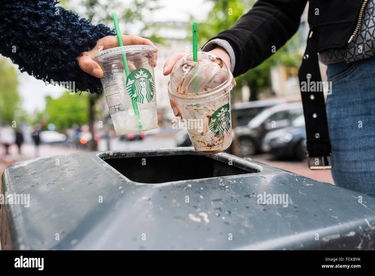 Gli adolescenti gettare i bicchieri di plastica nel bidone della spazzatura, Germania Foto Stock