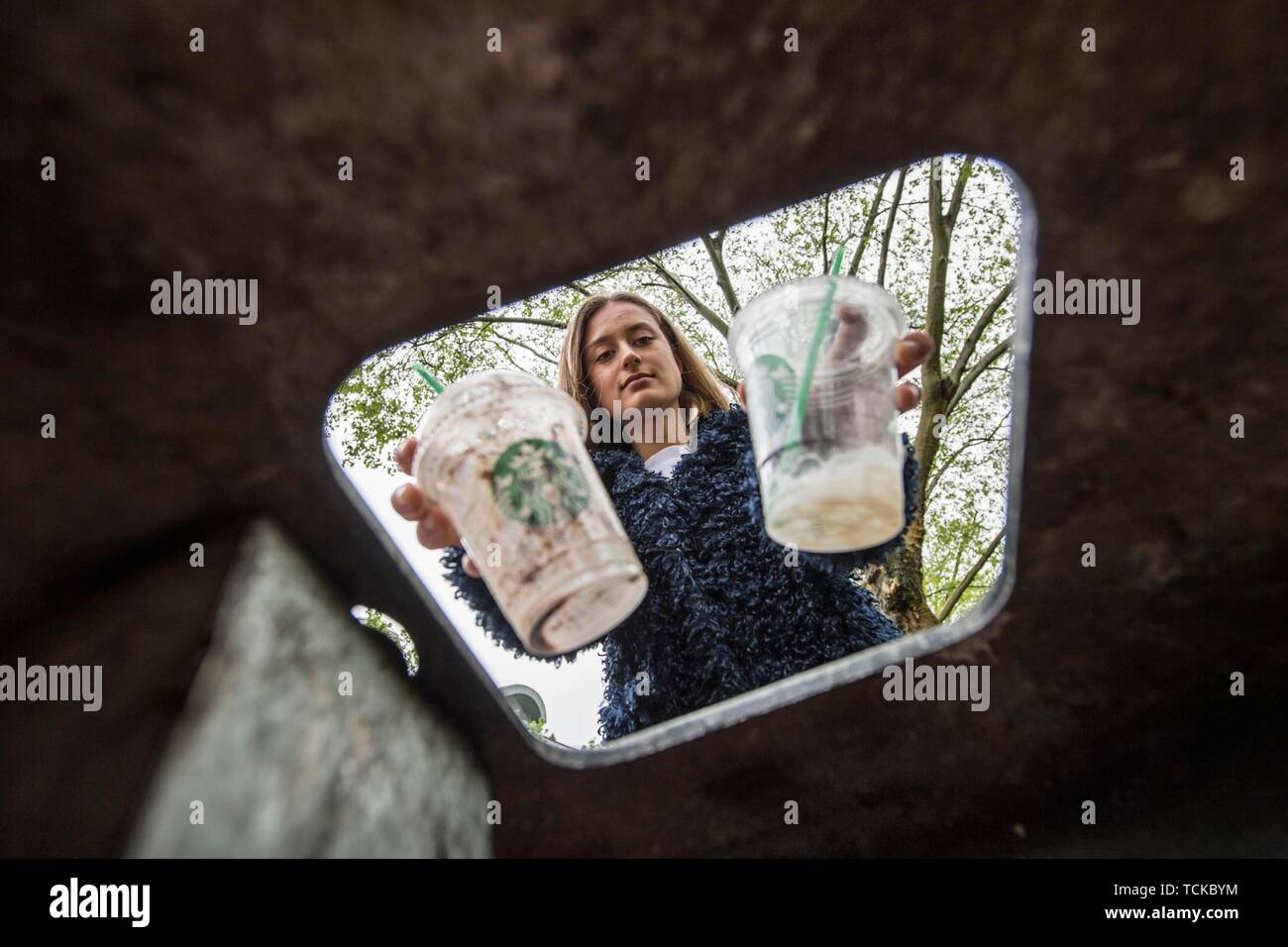 Adolescente getta una tazza di plastica nel bidone della spazzatura, Germania Foto Stock
