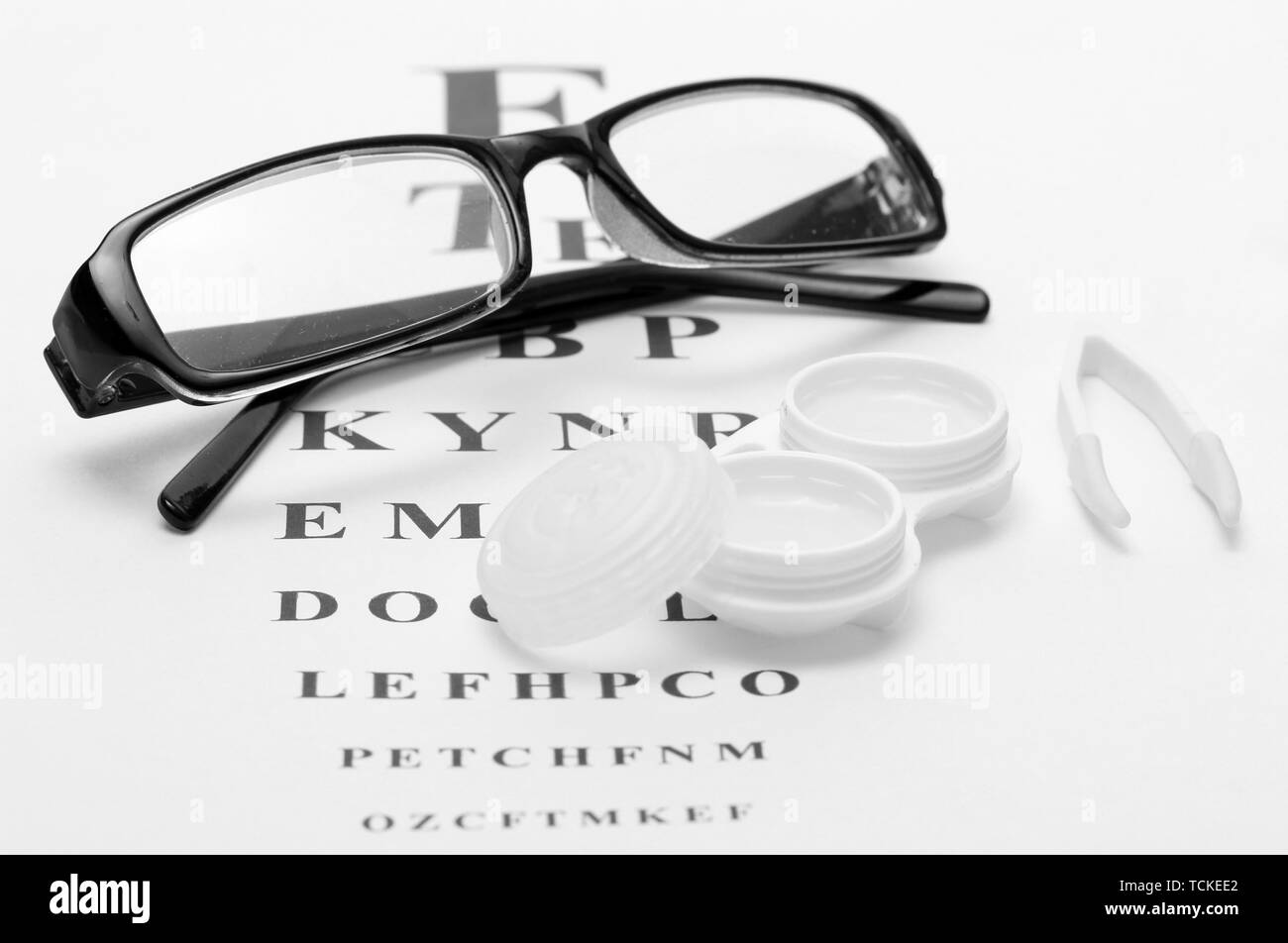 Occhiali, lenti a contatto in contenitori e pinzette, sul occhio snellen sfondo grafico Foto Stock