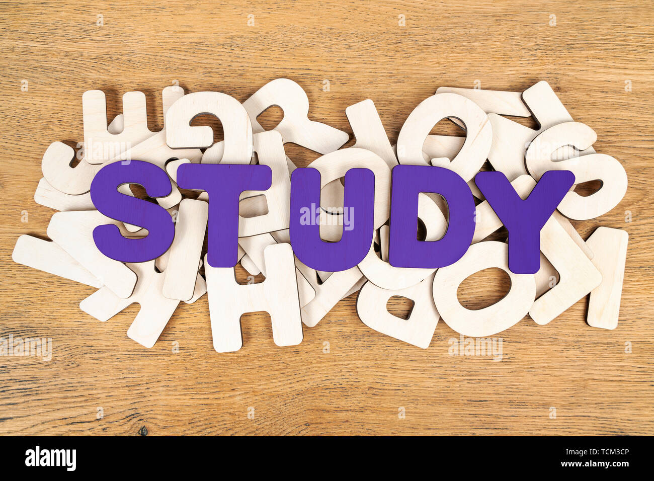 Violetta parola studio, stabiliti di lettere in legno su un mucchio di lettere diverse giacenti su una scrivania in legno Foto Stock
